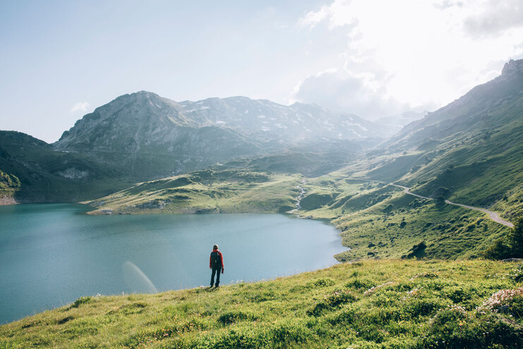 Eine Person steht vor einem Gebirgssee