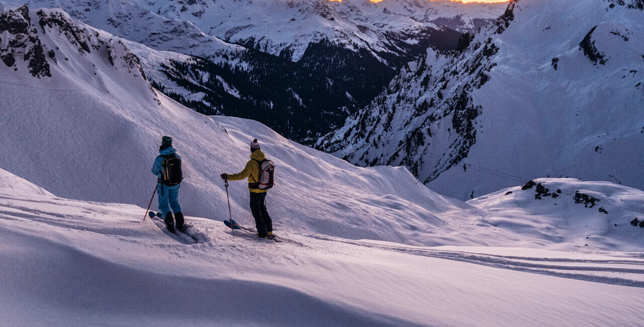 Zwei Skifahrer vor Bergpanorama